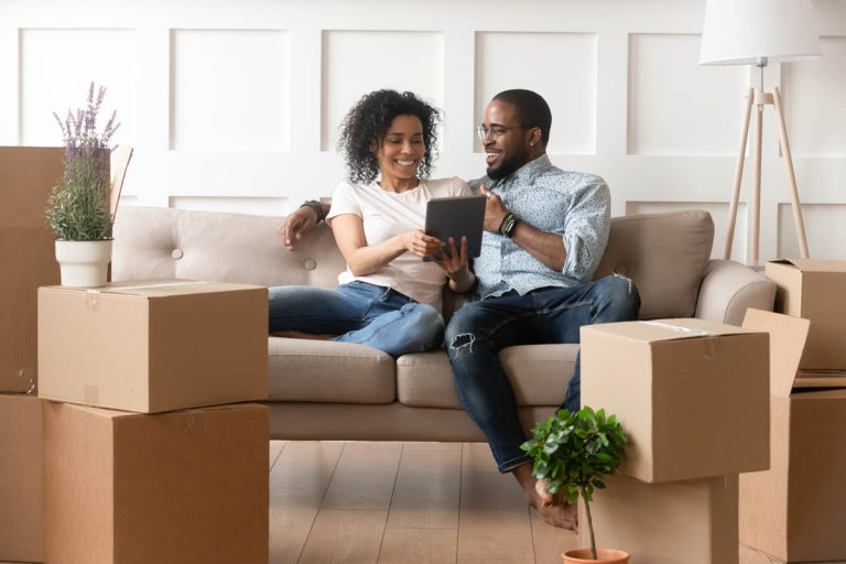 Couple sitting on couch in new home with unpacked boxes