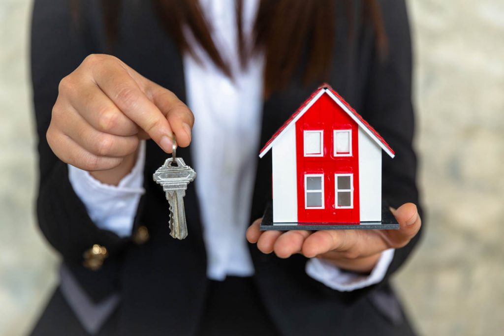 Hands holding house keys and model home